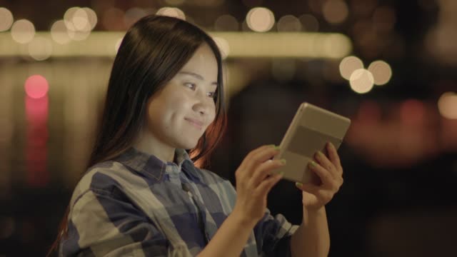Junge-Asiatin-mit-Tablet-in-den-Straßen-der-Stadt
