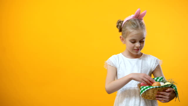 Adorable-schoolgirl-taking-pink-egg-from-basket,-holiday-background,-festival