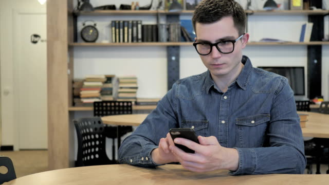 Kreative-junge-Mann-in-Gläsern,-Internet-surfen-und-mit-Smartphone
