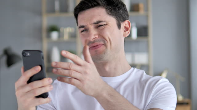 Sad-Young-Man-Reacting-to-Online-Failure-on-Smartphone