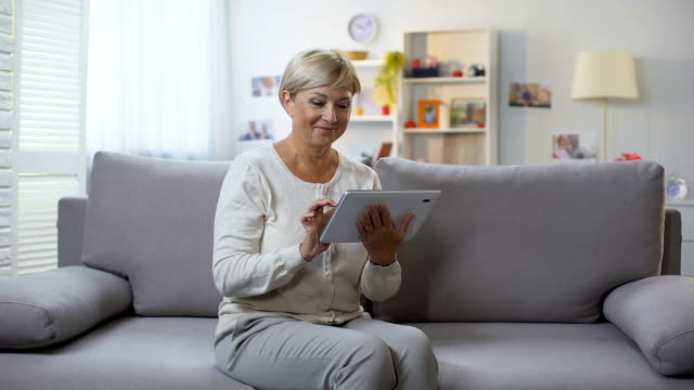 Ausgeschwungene-weibliche-Scroll-Tablet-Anwendung-entspannend-zu-Hause,-Online-Shopping