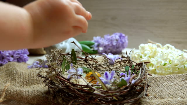 Child's-hand-puts-colored-egg-in-in-the-Easter-nest