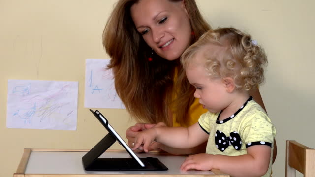 Babysitter-teaching-little-child-girl-using-tablet-computer