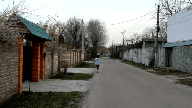 Alone-woman-walks-along-the-road-among-the-houses-and-trees.