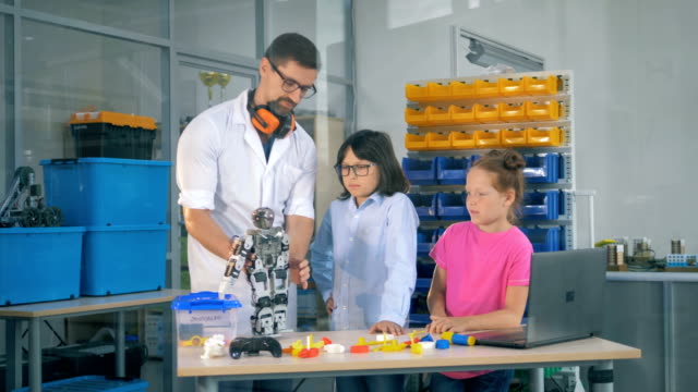 Lehrerin-zeigt-Kinder-Roboter-in-Technik-Wissenschaftsklasse