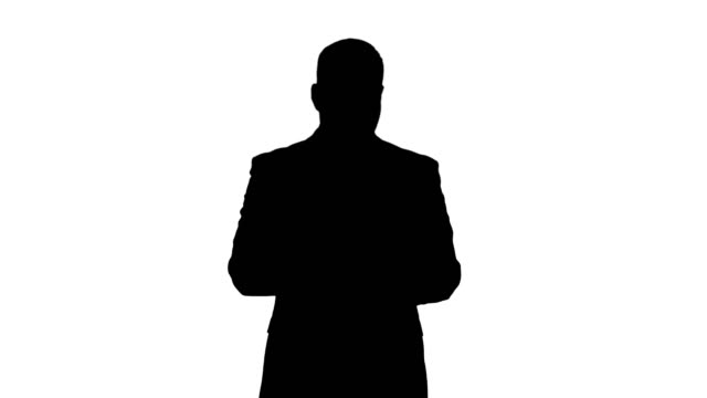 Silhouette-Businessman-swiping-pages-on-a-tablet-and-talking-to-camera-explaining-something-while-walking