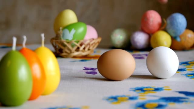 Easter.-male-hand-turns-a-brown-chicken-egg-on-the-table.-olorful-Easter-eggs-in-the-background.