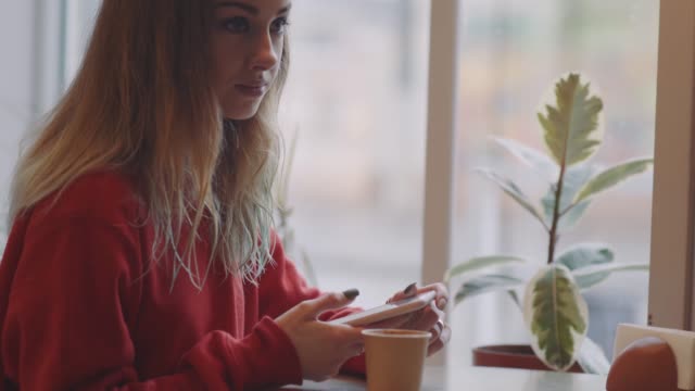 Lächelnde-Frau-im-Café-mit-Handy-und-Textnachrichten-in-sozialen-Netzwerken,-allein-sitzen