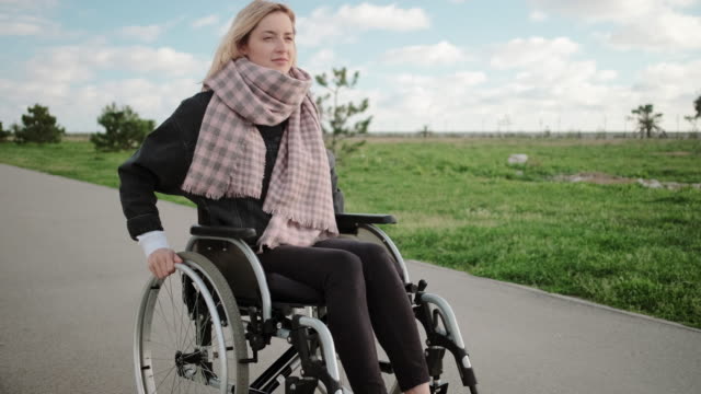 Junge-behinderte-Frau-reitet-im-Frühling-auf-dem-Rollstuhl-im-Parkgelände