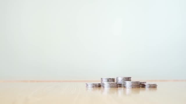 Stop-motion-increasing-pile-of-silver-coins-on-wooden-table-at-right-corner-with-white-color-background