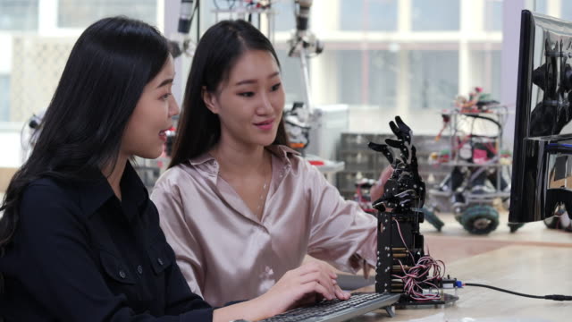 Asiatische-junge-Elektroniker-versuchen,-Roboter-im-Labor-zu-beheben.-Technologie--und-Innovationskonzept.