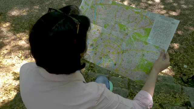 Middle-aged-brunette-looks-at-a-paper-map-in-the-park