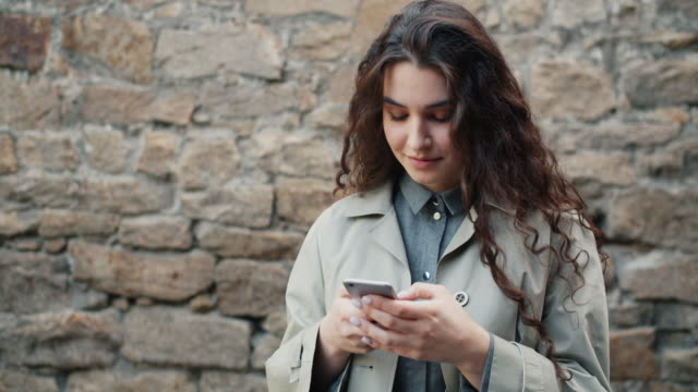Slow-motion-of-pretty-girl-using-smartphone-in-street-touching-screen-smiling