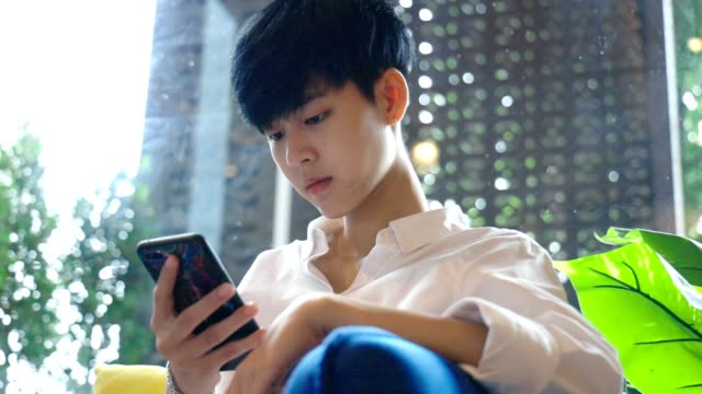 Junge-asiatische-Frau-mit-Blick-auf-mobiles-Smartphone