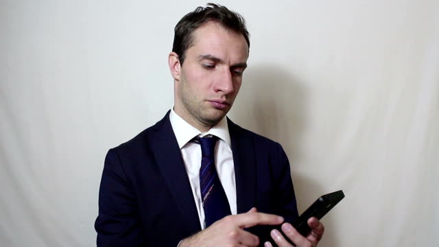 Young-handsome-businessman-pulls-out-his-smartphone-from-his-pocket-and-looks-through-the-news-feed.