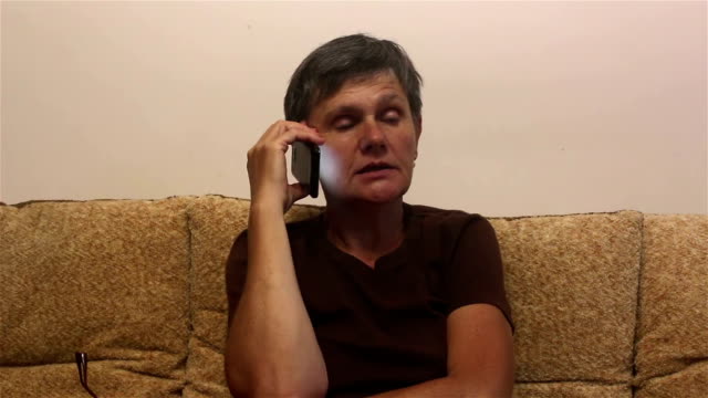 Attraktive-erwachsene-Frau-macht-einen-Anruf-auf-ihrem-Smartphone,-sitzen-auf-einem-Sofa-zu-Hause.