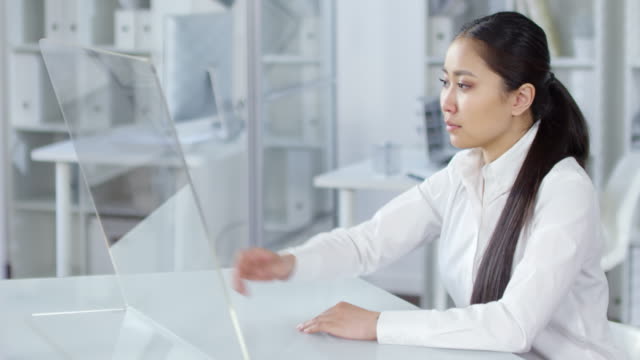 Mujer-Asiática-Joven-usando-pantalla-táctil-TRANSPARENTE-de-AR-en-la-oficina