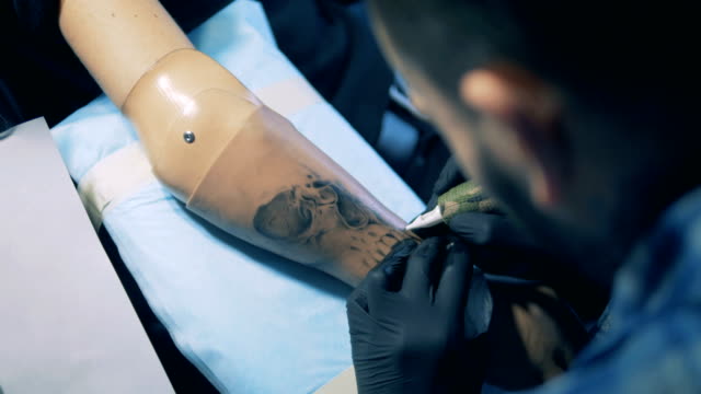 Schwarz-Tinte-Tattoo-wird-auf-einem-männlichen-Prothesenarm-gemacht