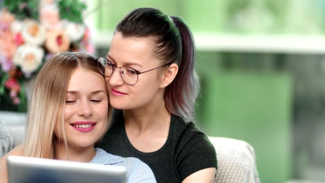 Tenderness-same-sex-couple-enjoying-watching-tablet-pc-entertainment-kissing-feeling-love-close-up