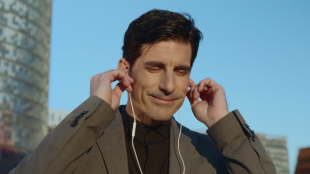 Businessman-putting-earphones-at-street.-Employee-listening-music-in-earbuds