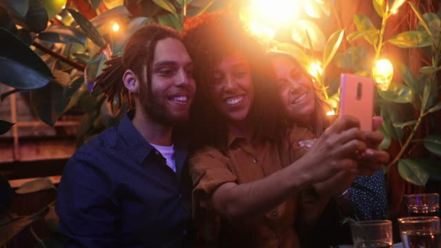 Close-up-black-woman-taking-selfie-with-friends-during-meal