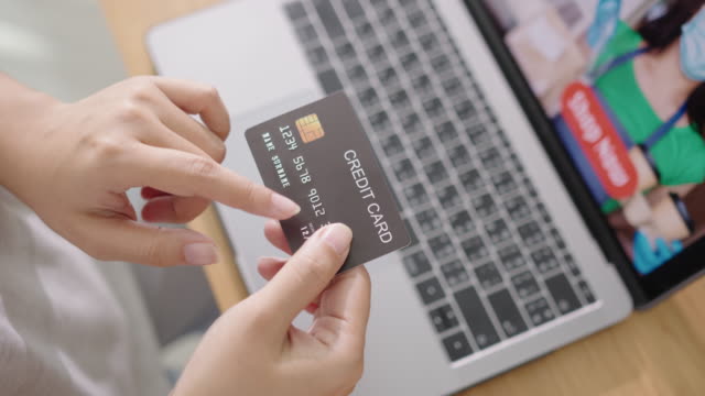 Close-up-consumer-woman's-hand-holding-credit-card-making-e-bank-online-payment-for-purchase-in-online-website-store-with-laptop-computer.-Ecommerce-website-payments.-new-normal-digital-lifestyle