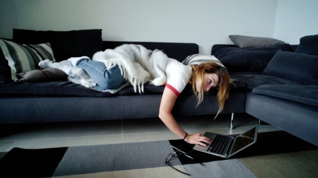 Mujer-joven-aburrida-pone-en-sofá-charlas-sobre-ordenador-portátil-redes-sociales