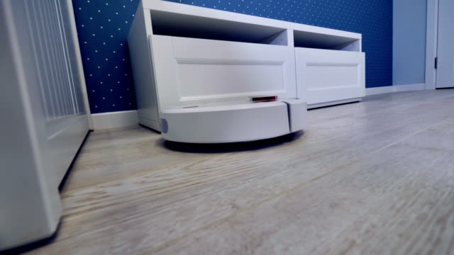A-robotic-vacuum-moves-along-several-pieces-of-white-furniture.