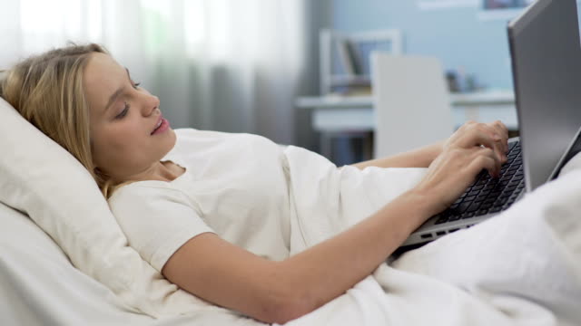 Teenage-girl-lying-in-bed-with-laptop,-social-networking-addiction-problem