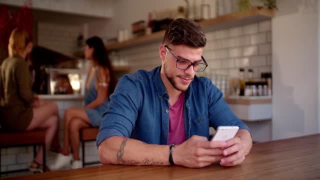 Junge-Hipster-Mann-SMS-auf-Handy-bei-urban-Cafe