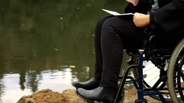 traurig-und-einsam-Frau-im-Rollstuhl-schreibt-Tagebuch