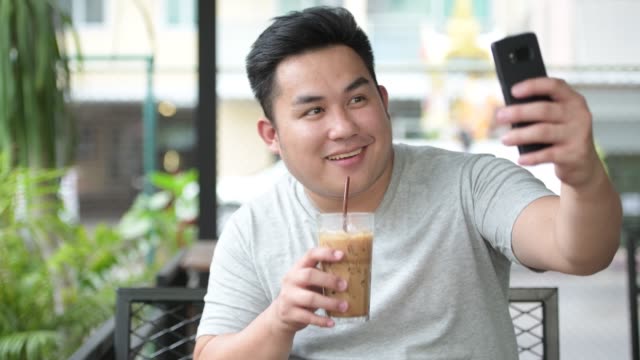 Junge-hübsche-Übergewicht-asiatischer-Mann-entspannend-im-Coffee-shop