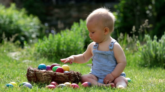 Cute-child,-playing-with-little-bunny-and-easter-eggs-in-a-blooming-garden,-springtime.-Boy-play-with-rabbit,-egg-hunting-for-holiday