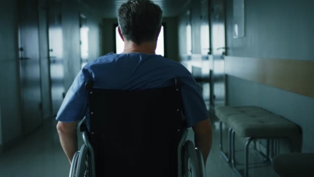 Im-Krankenhaus-Vorderansicht-nach-Schuss-von-der-ältere-Mann-im-Rollstuhl-bewegen-durch-den-Flur.