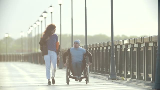 Hombre-discapacitado-en-silla-de-ruedas-caminar-juntos-a-su-novia-en-el-muelle