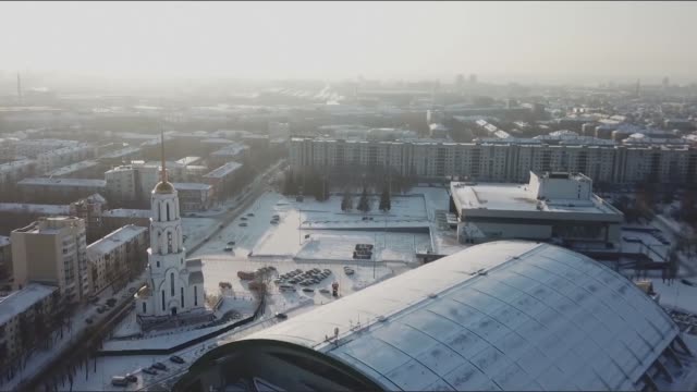 Aerial-view-of-Church-in-Russia.-Aerial-view-of-an-urban-cityscape-of-a-town-with-a-crossing-river-in-wintertime.-Stock.-White-snow-covered-roofs-and-snow-all-over-the-city