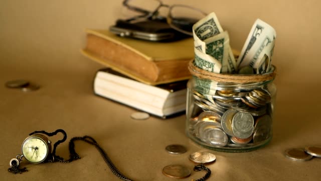 Bücher-mit-Penny-Glas-gefüllt-mit-Münzen-und-Banknoten.-Studiengebühren-oder-Bildung-Finanzierungskonzept.-Stipendium-Geld.