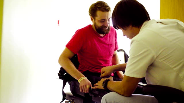 Doctor-poniendo-el-exoesqueleto-robótico-para-hombre-discapacitado