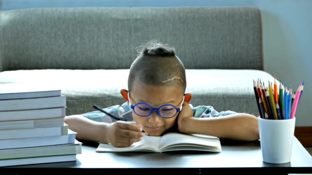Junge-mit-Behinderung,-Störungen-des-Gehirns-und-linkes-Auge-ist-nicht-sichtbar-von-Gehirnchirurgie.-Er-ist-denken-und-Schreiben-in-Buch,-glückliches-Lächeln-zu-Hause.-Bildungskonzept