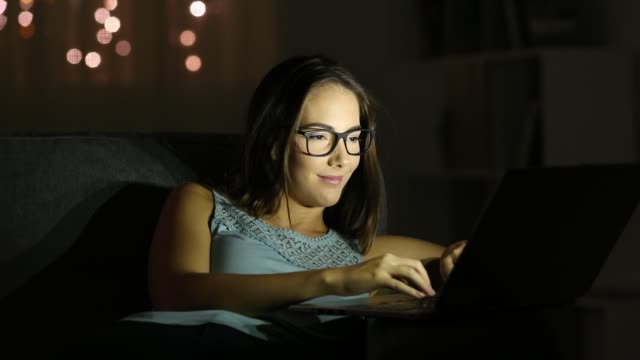 Mujer-con-anteojos-usando-una-laptop-en-la-noche