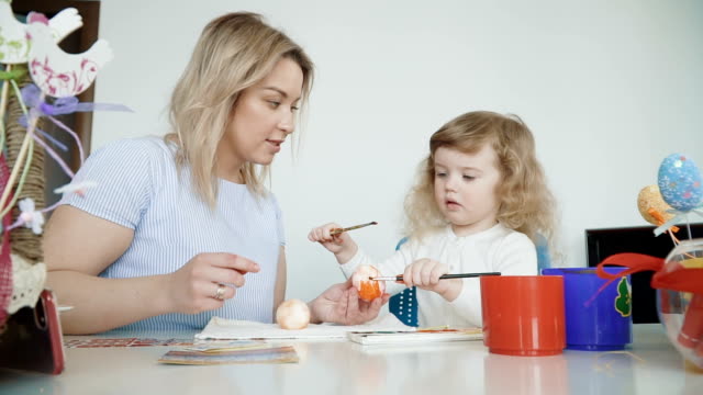 Madre-y-su-pequeña-hija-pintando-huevos-de-Pascua