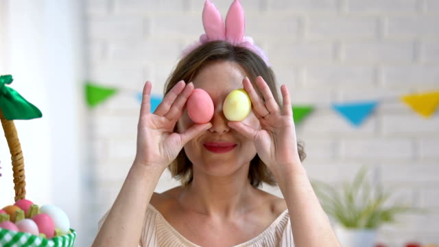 Bella-dama-jugando-con-huevos-de-Pascua-teñidos-teniéndolos-cerca-ambiente-festivo-ojos