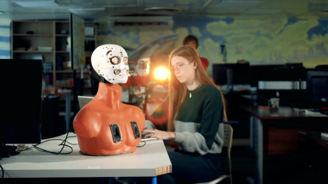Junges-Mädchen-steuert-einen-Roboter-auf-einem-Tisch.-Futuristische-Humanoid-und-Ingenieur.