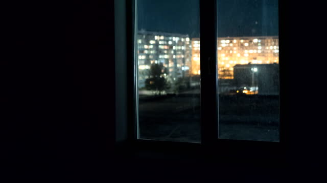 Vista-a-través-de-la-ventana-en-las-luces-de-las-ventanas-en-edificios-de-gran-altura-en-la-noche