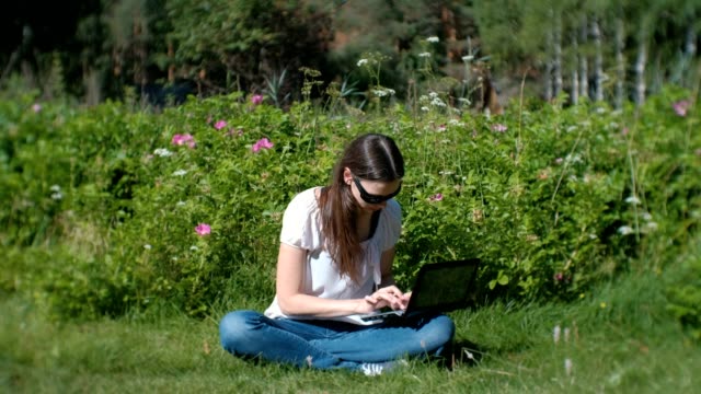 Schöne-Brünette-Mädchen-arbeiten-Tippen-auf-Laptop-sitzen-im-Park-im-Sommer.