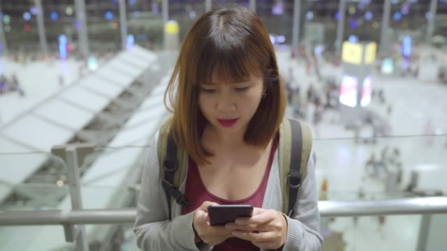 Asiatische-Frau-mit-ihrem-Smartphone-auf-internationalem-Flughafen.