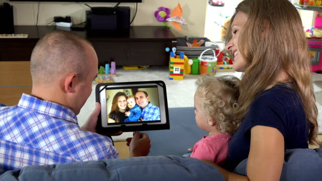 Mann-Frau-und-kleine-Mädchen-beobachten-Familienfotos-auf-Tablet-PC-zu-Hause