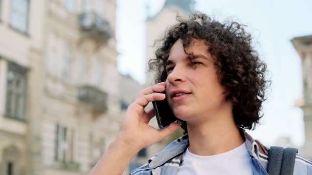 Close-up-portrait-of-young-man-talking-on-smartphone.-Happy-young-casual-guy-using-cell-phone-outside,-in-a-city-centre.-Portrait-of-a-handsome-hipster-talking-on-the-phone-and-smiling.