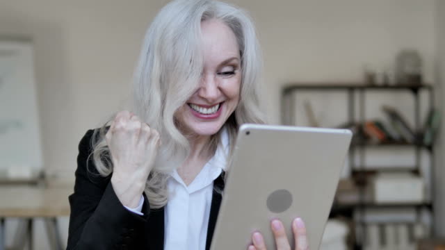 Old-Business-Woman-Cheering-Win-on-Tablet