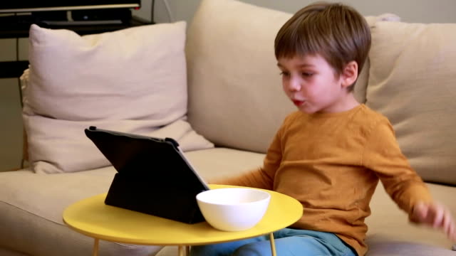 Niño-usando-Tablet-PC-en-la-cama-en-casa.-Niño-lindo-en-el-sofá-está-viendo-dibujos-animados,-jugando-juegos-y-aprendiendo-desde-el-ordenador-portátil.-Educación,-diversión,-ocio,-felicidad,-tecnología-informática-moderna-y-comunicación.